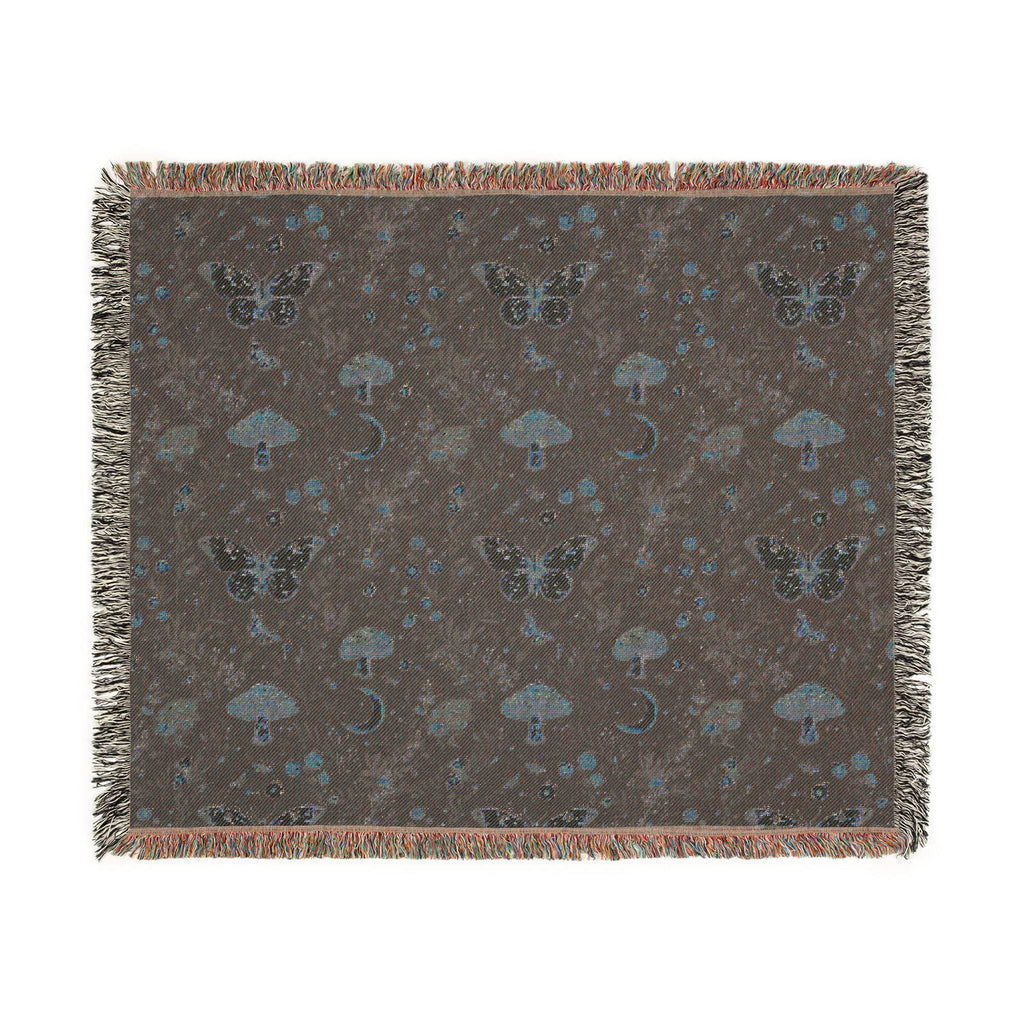 A square woven throw blanket with fringe edges, featuring a dark brown background patterned with butterflies, mushrooms, and small blue celestial motifs.