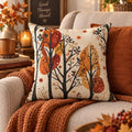 Autumn trees throw pillow with burnt orange and russet fall leaves on a soft cream background