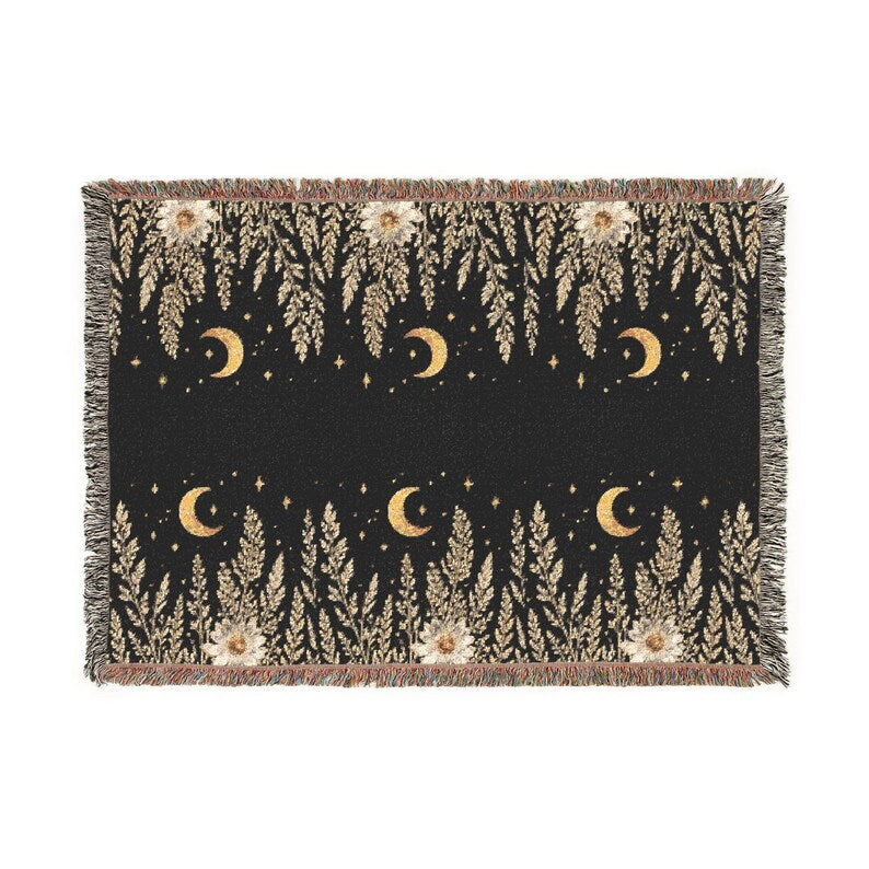 Black woven throw blanket with gold crescent moons, stars, cascading botanical foliage and cream floral accents