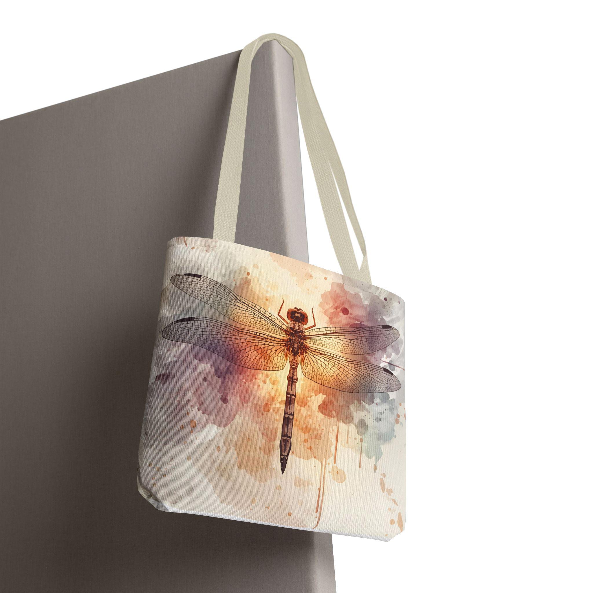 Watercolor Dragonfly Tote Bag hanging — vintage dragonfly illustration on soft watercolor wash background in cream, blush, and sage tones, natural canvas handle
