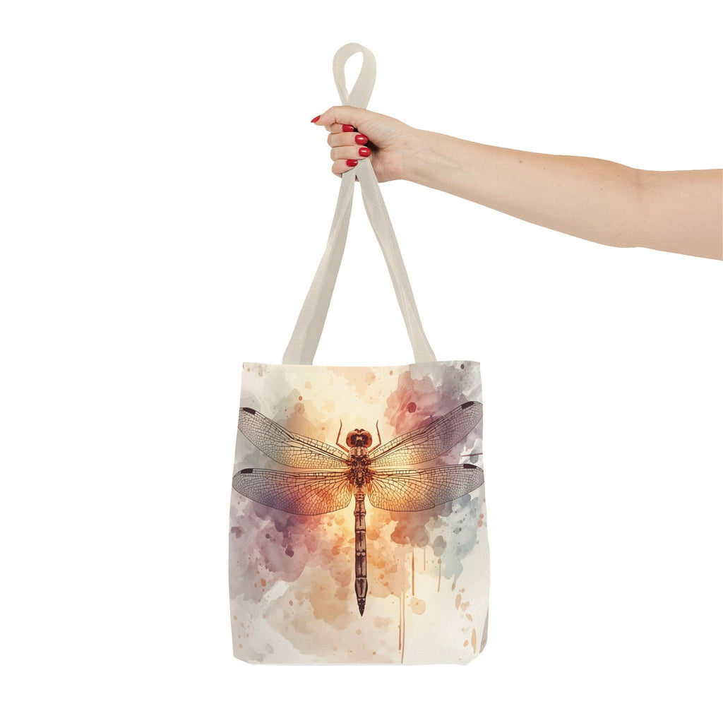 Watercolor Dragonfly Tote Bag held by handle — vintage dragonfly illustration on soft watercolor wash background in cream, blush, and sage tones, natural canvas handle

