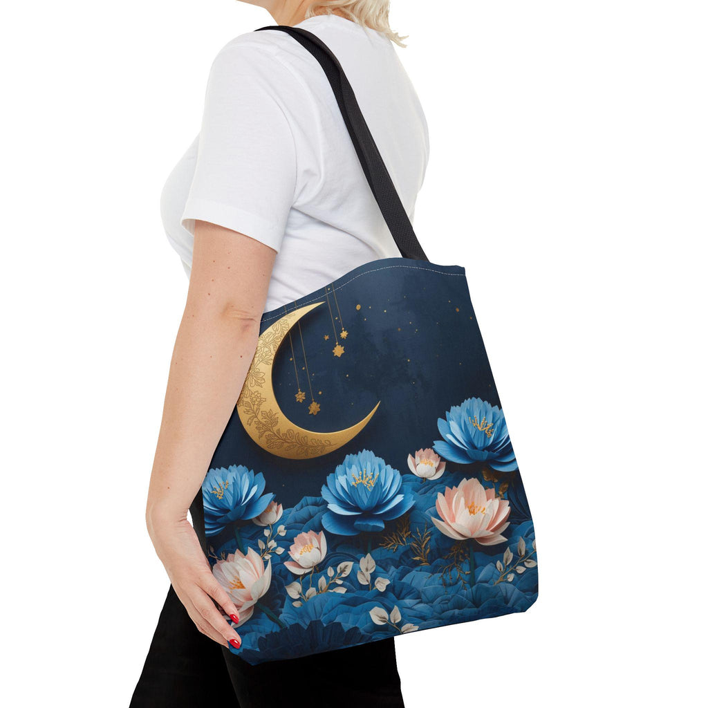 Person holding a blue tote bag with floral and moon design