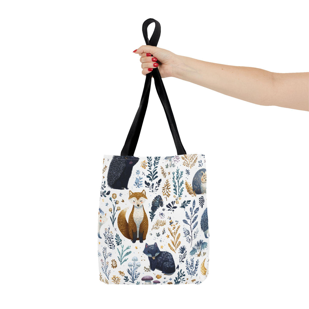 Woodland Fox and Hedgehog Tote Bag held by handle — forest animal print with foxes, hedgehogs, and floral sprigs in navy, amber, and gray, black handle