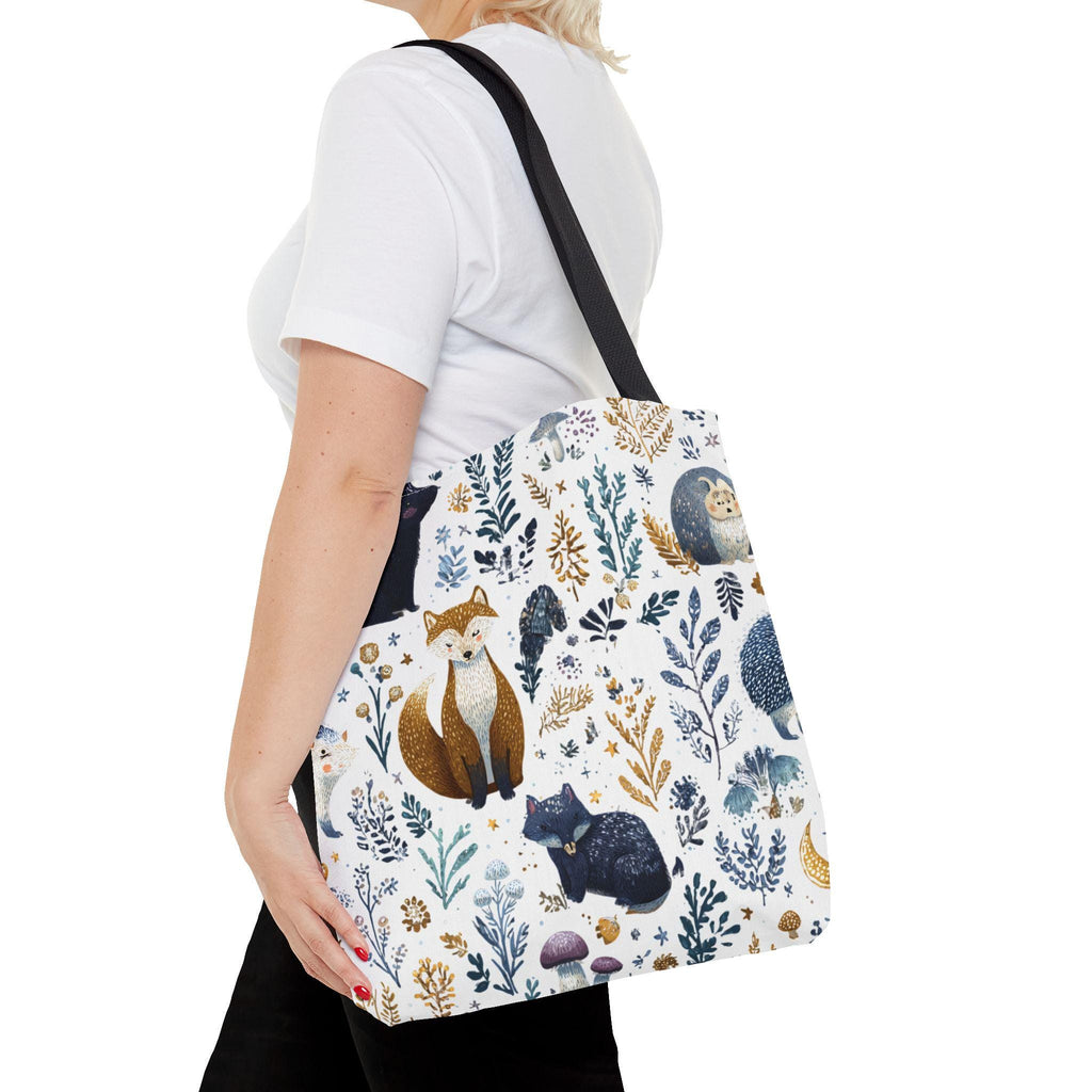 Woman wearing Woodland Fox and Hedgehog Tote Bag on shoulder — forest animal print with foxes, hedgehogs, and floral sprigs in navy, amber, and gray, navy handle, side view

