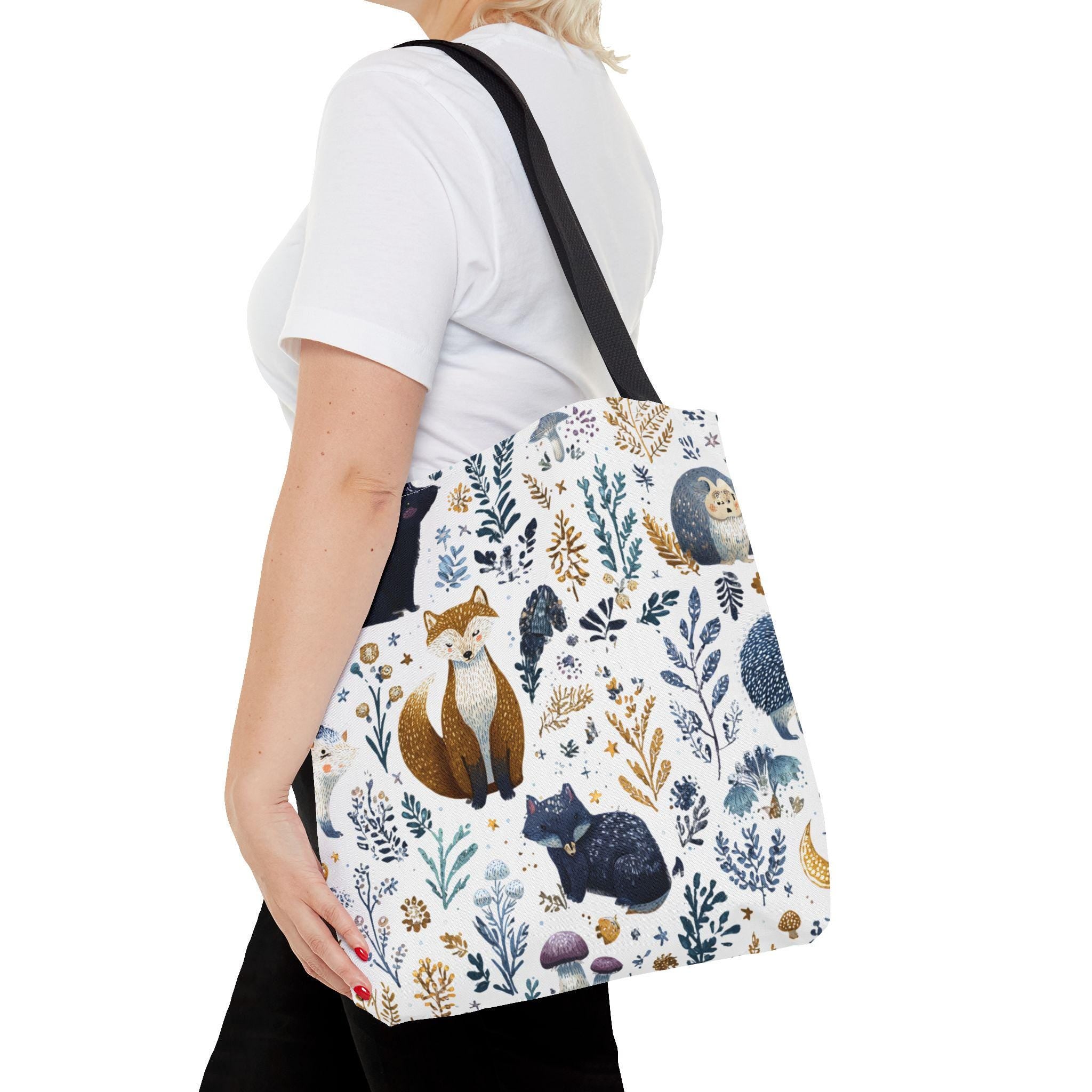 Woman wearing Woodland Fox and Hedgehog Tote Bag on shoulder — forest animal print with foxes, hedgehogs, and floral sprigs in navy, amber, and gray, navy handle, side view

