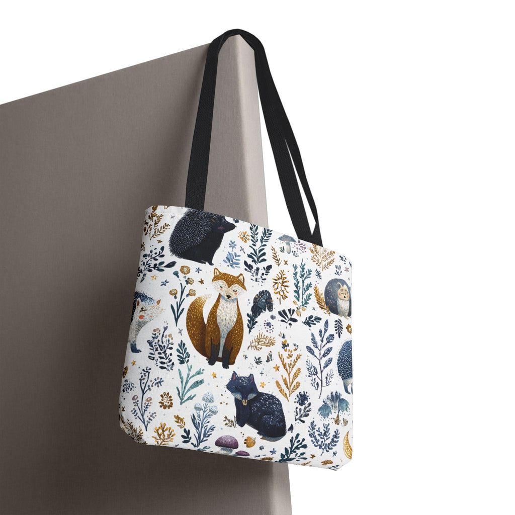 Woodland Fox and Hedgehog Tote Bag hanging against neutral backdrop — forest animal print with foxes, hedgehogs, and floral sprigs in navy, amber, and gray, black handle, close-up detail