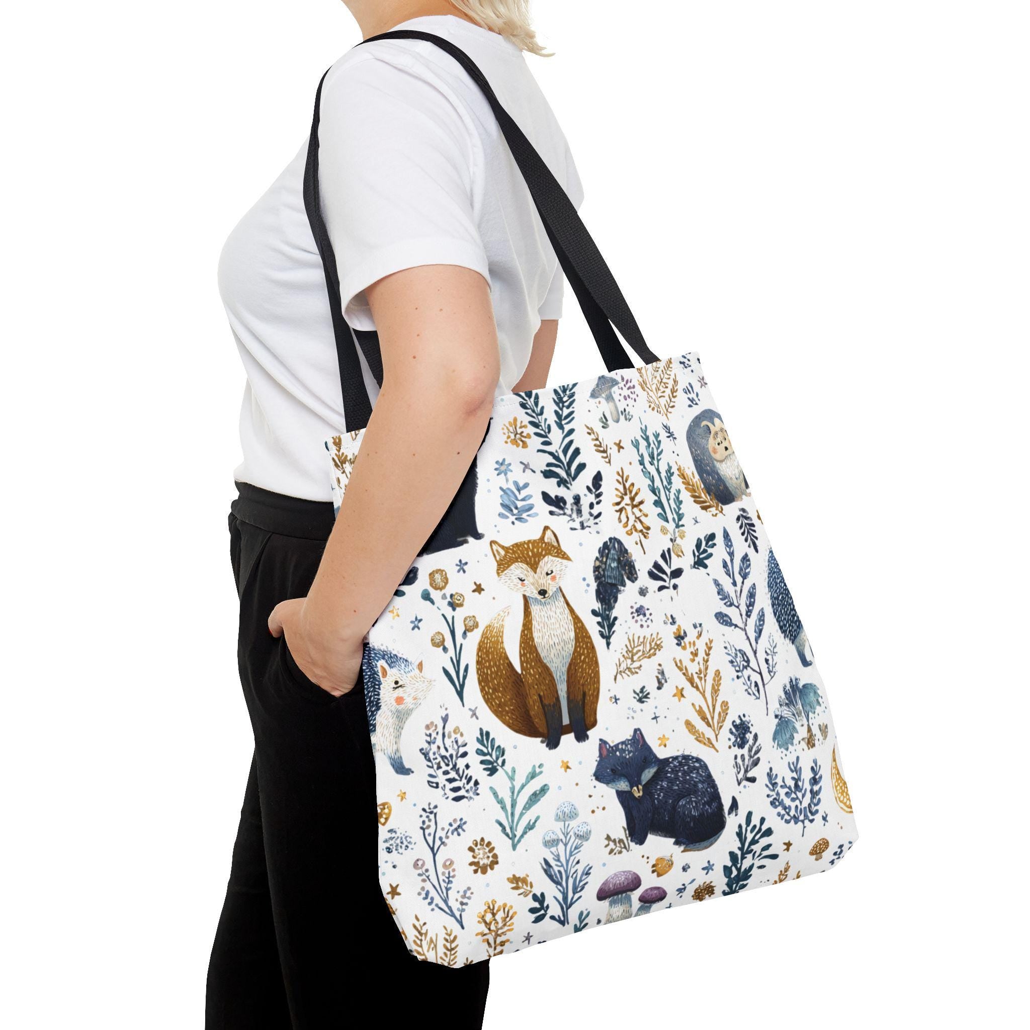 Woman carrying Woodland Fox and Hedgehog Tote Bag at side — forest animal print with foxes, hedgehogs, and floral sprigs in navy, amber, and gray, navy handle, back view