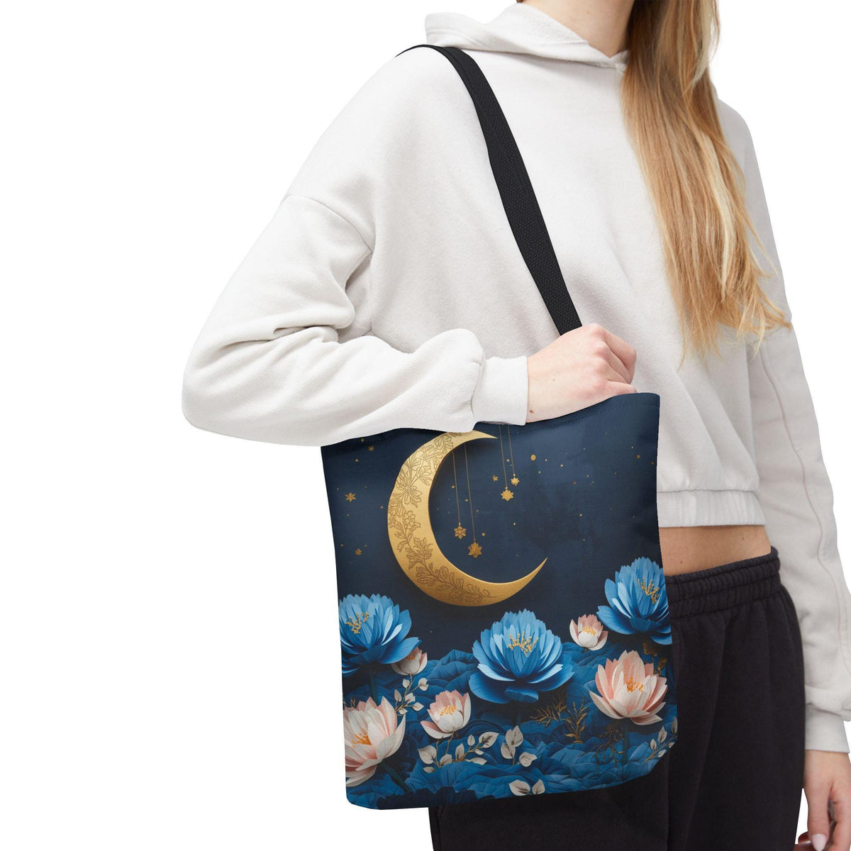 Person holding a tote bag with floral and moon design