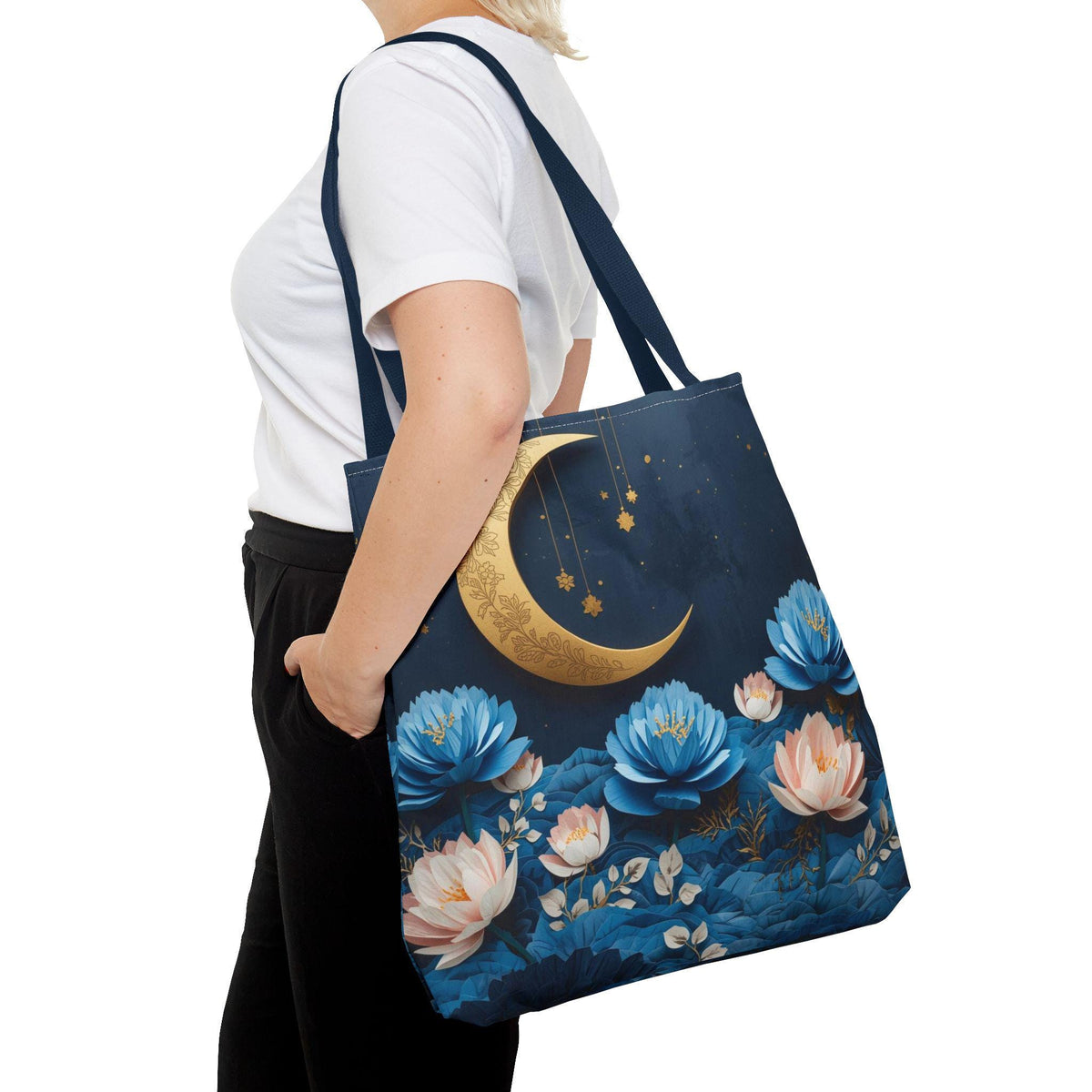 Person holding a tote bag with floral and moon design on a white background