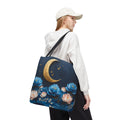 Person wearing a white hoodie and beige cap, carrying a tote bag with floral and moon design.