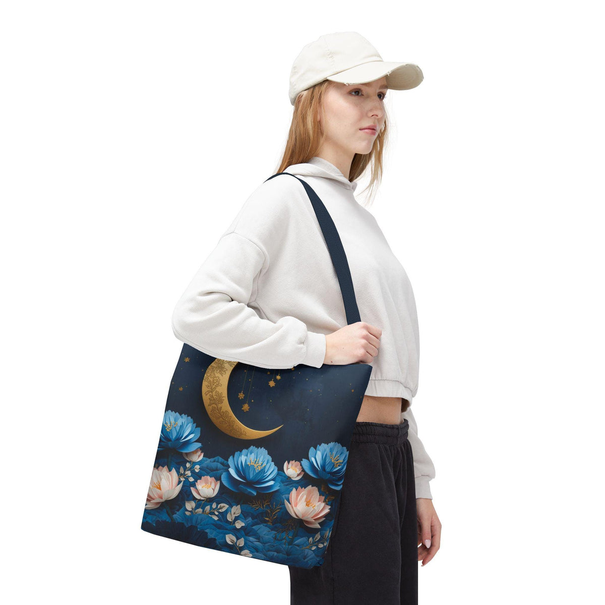 Person holding a tote bag with floral and moon design on a white background
