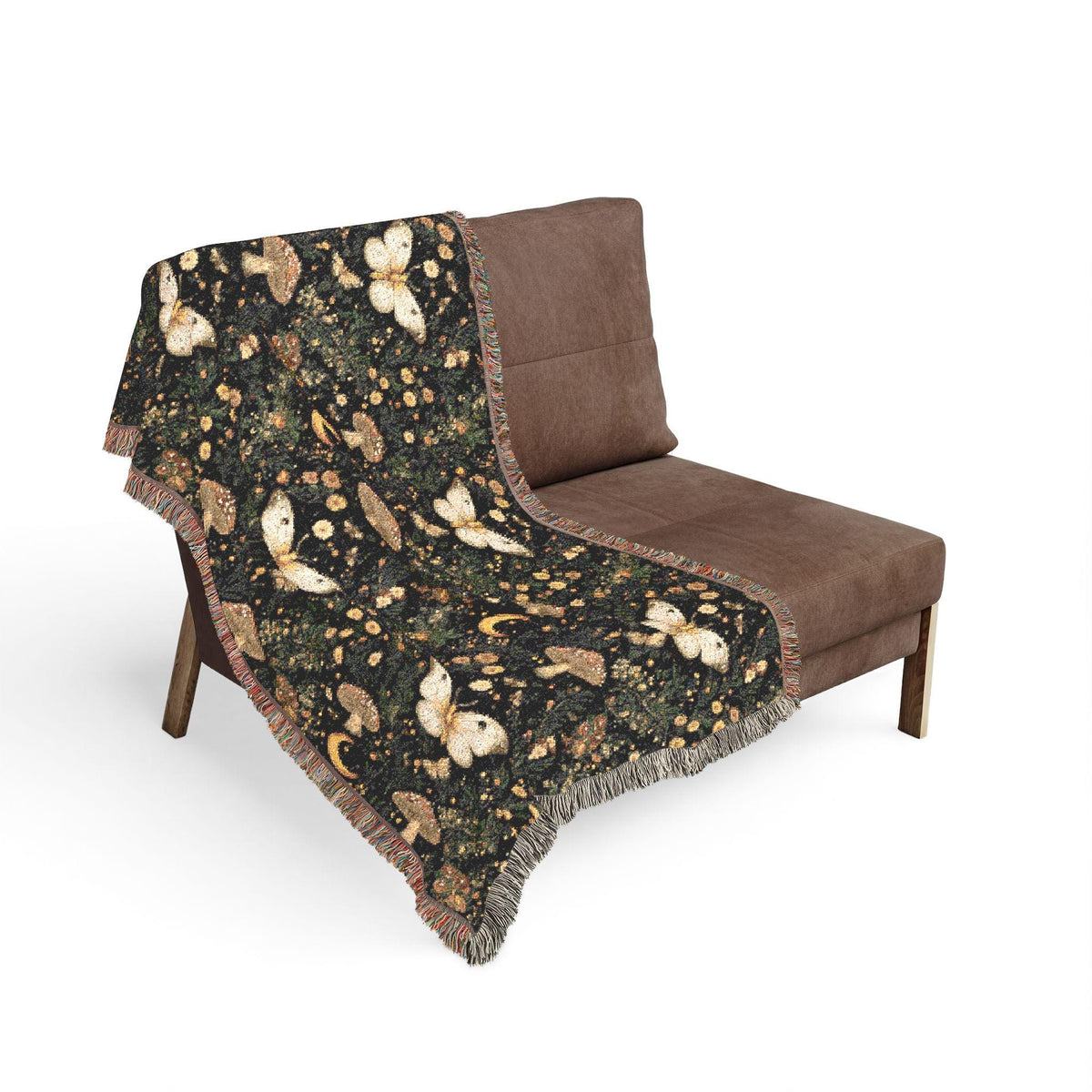 A black woven throw blanket with a cream sheep pattern and fringed edges, draped over a brown lounge chair against a plain white background.