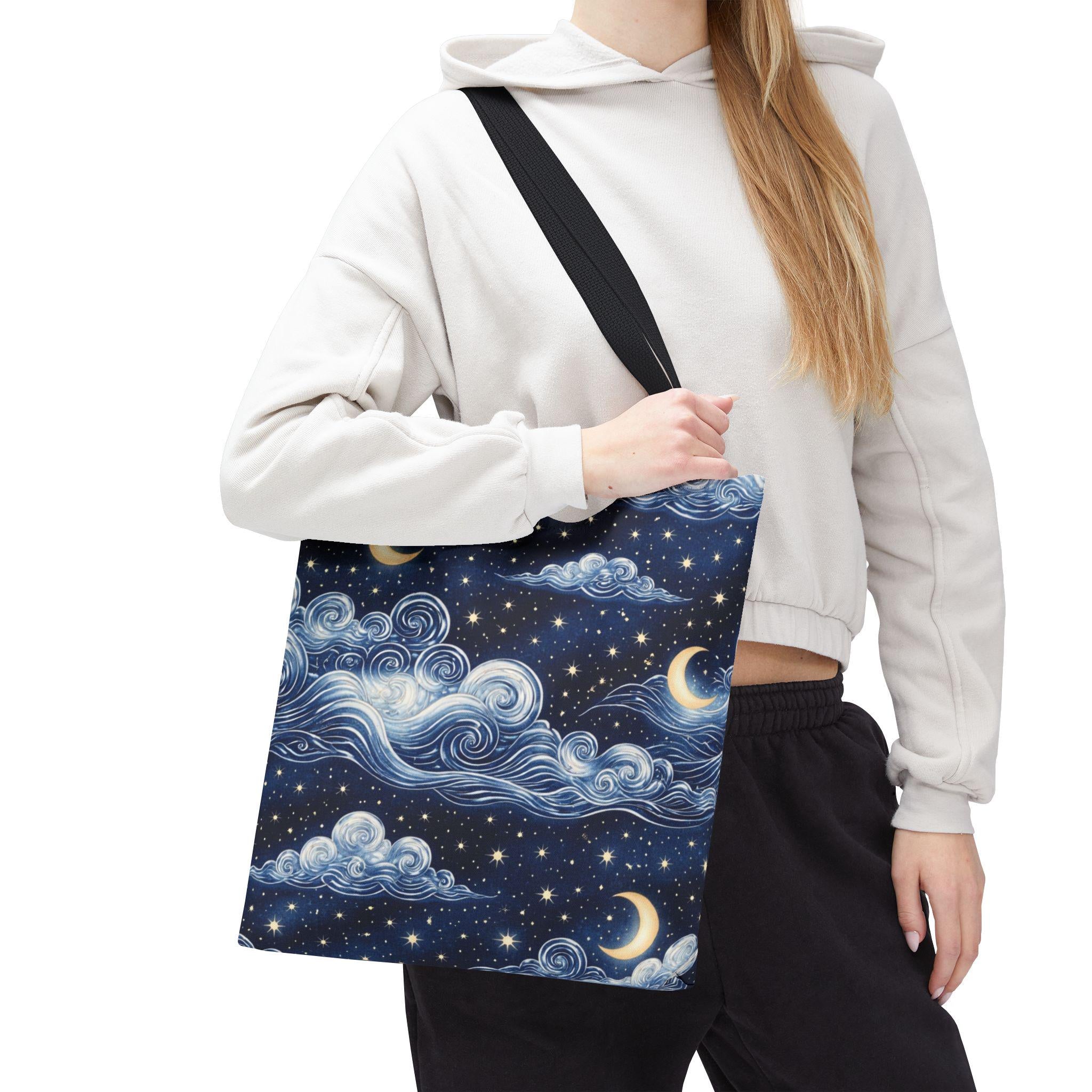 Moon and whimsical clouds tote bag carried by hand — navy night sky swirling clouds and crescent moon print tote bag
