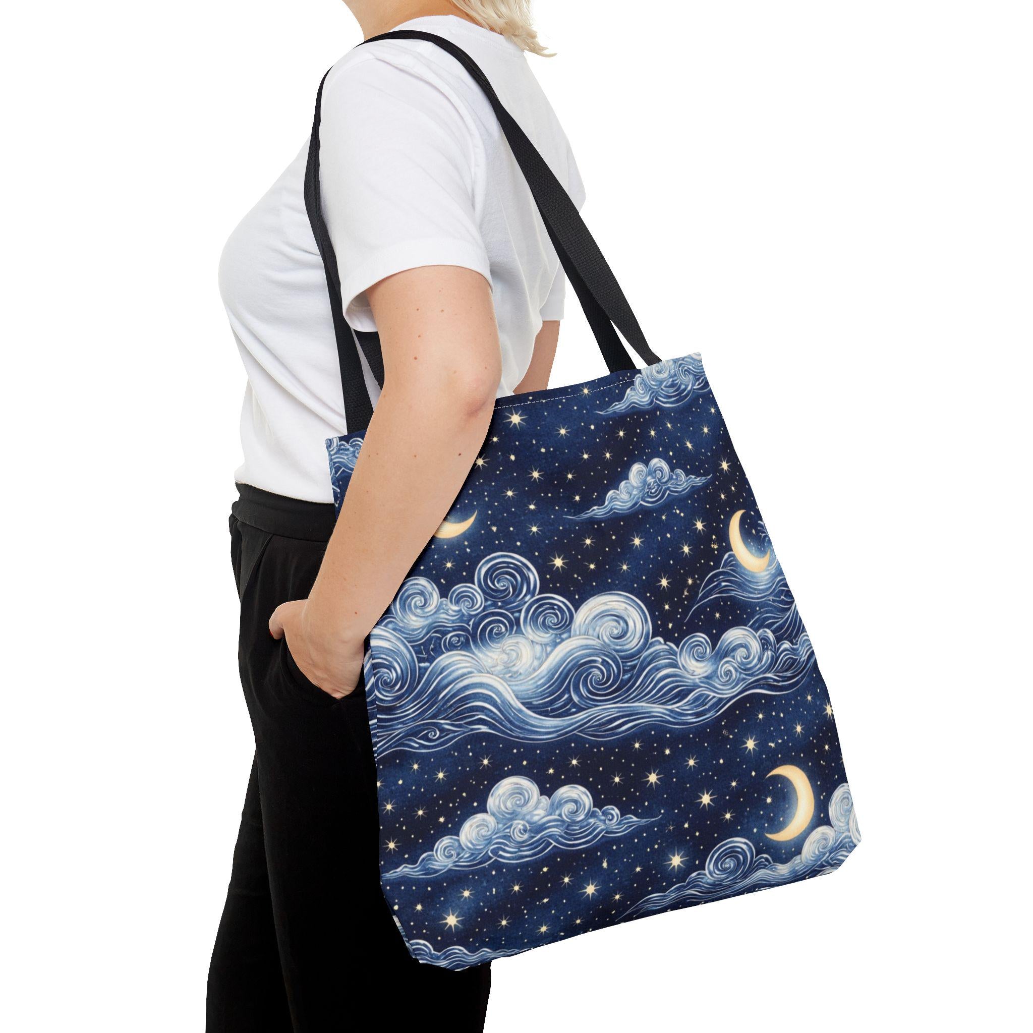 Moon and whimsical clouds tote bag worn over shoulder front view — navy night sky swirling clouds crescent moon and star print tote