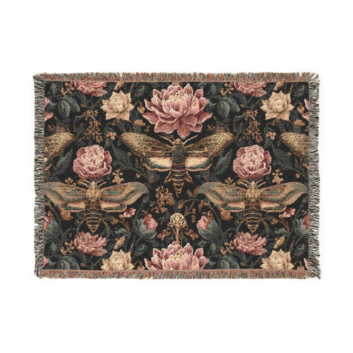 A rectangular woven tapestry with fringed edges, featuring a dark background with large pink flowers, moths, and butterflies in muted gold, beige, and olive tones.